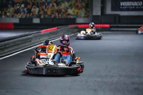 Doi copii cu căști colorate împart un kart dublu pe circuitul indoor Red Motor