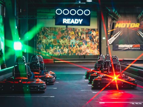 Karturi electrice CRG aliniate pe grila de start Red Motor, sub semaforul READY și lumini laser