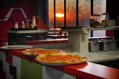 Pizza proaspăt scoasă din cuptor pe barul Zonei Relax, cu circuitul în fundal la apus