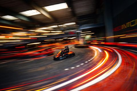 Kart în viteză pe circuitul Red Motor noaptea, cu dâre de lumină roșii în jurul pistei