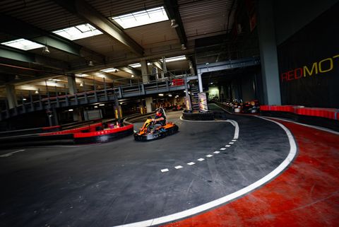 Vedere de ansamblu a circuitului indoor Red Motor, cu pista neagră cu borduri roșii și un kart în viraj